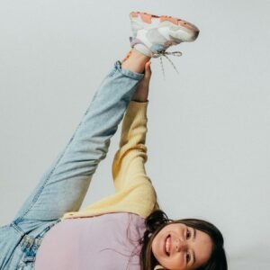 Cheerful girl in playful pose wearing casual outfit indoors with a bright smile.