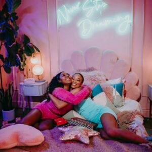 Two girls having fun in a colorful bedroom during a cozy sleepover party.